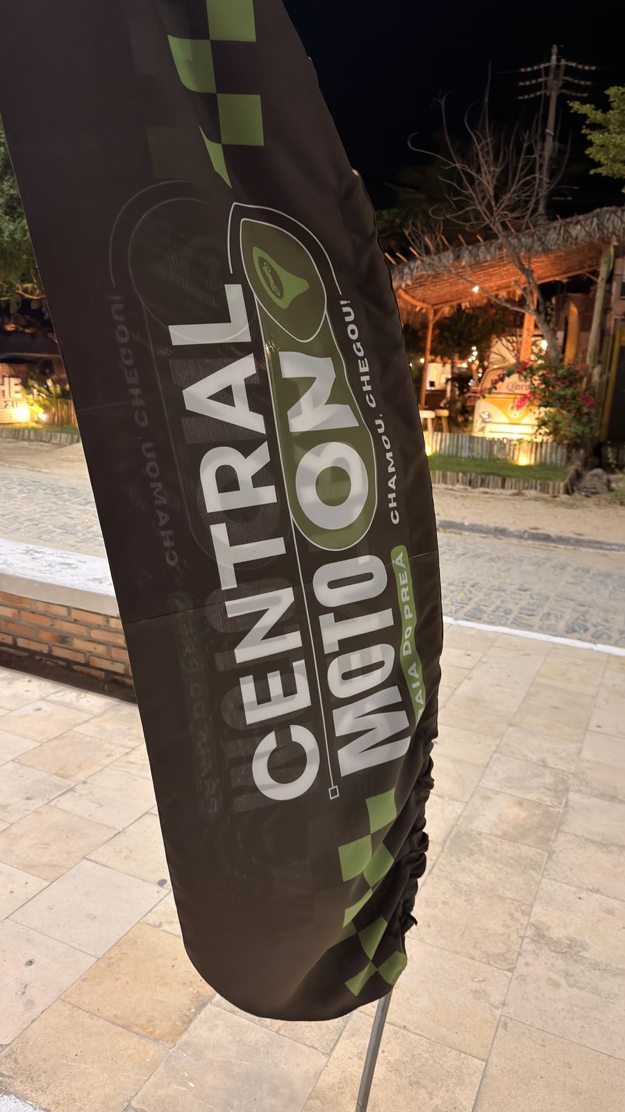 Bandeira da Central Moto On, serviço de mototáxi, na rua da Praia do Preá à noite