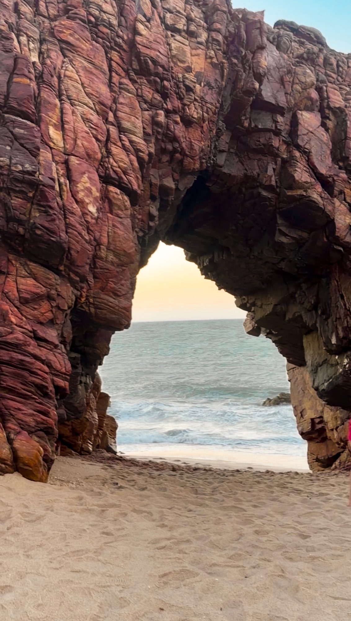 Pedra Furada, em Jericoacoara, com o mar e o fim de tarde vistos através do arco