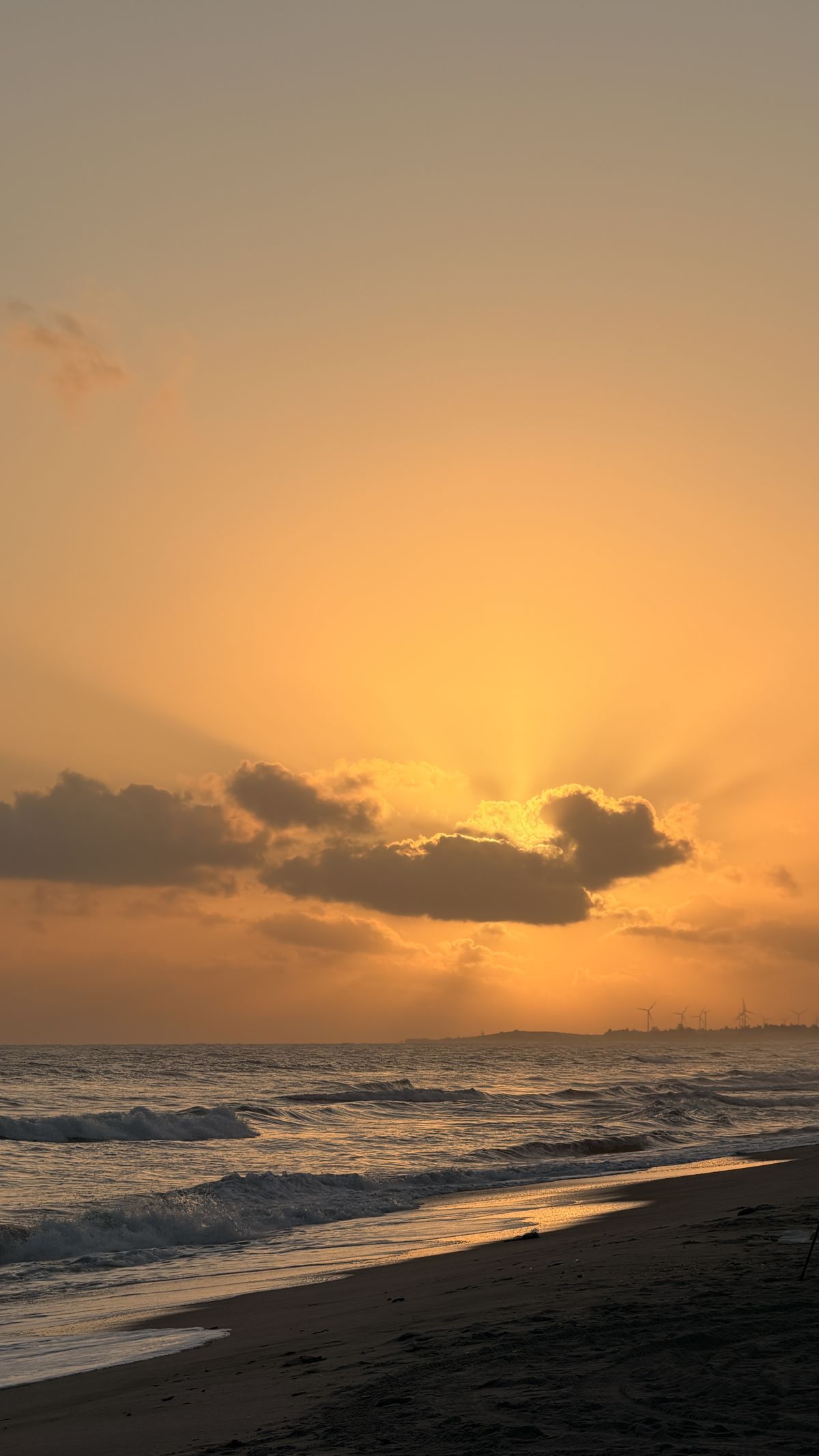 Amanhecer dourado na Praia do Preá, com o sol nascendo atrás das nuvens sobre o mar