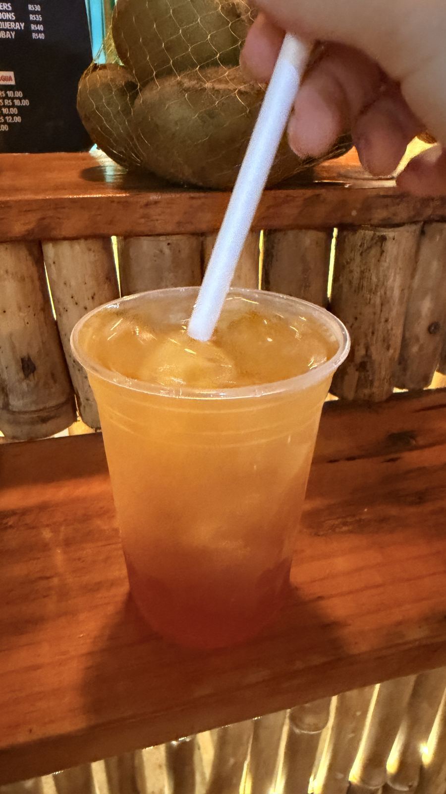 Drink gelado com canudo no balcão de madeira do El Trago, em Jericoacoara